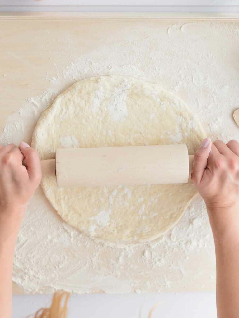 Rolling out pizza dough with a rolling pin.