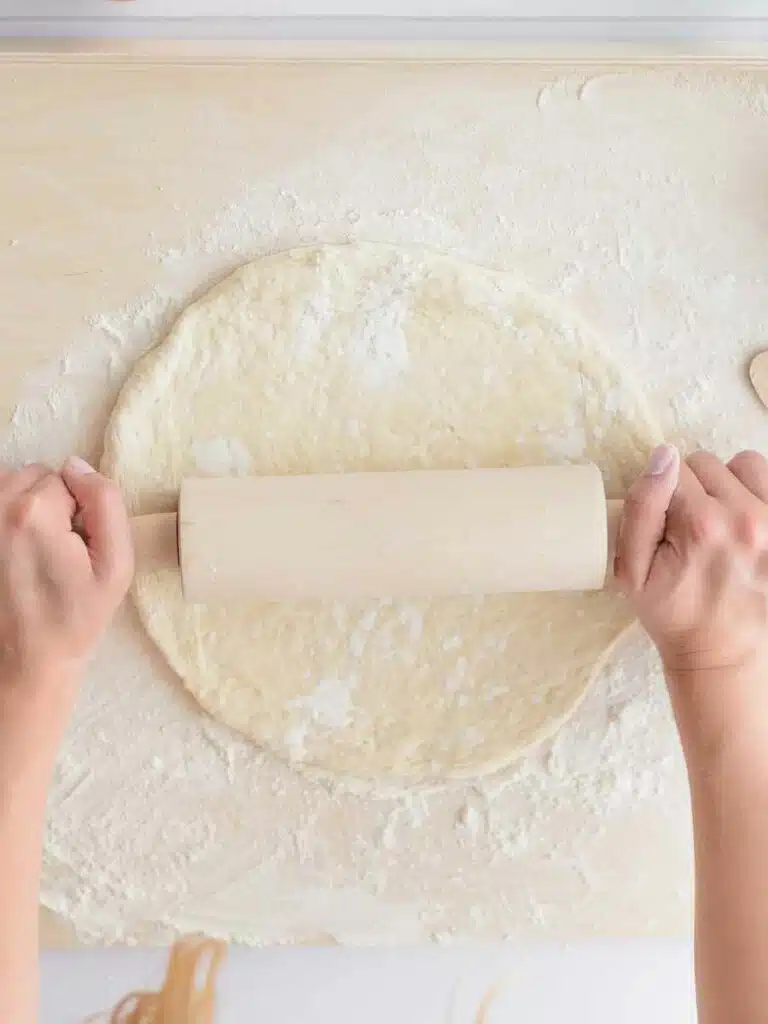 Rolling out pizza dough with a rolling pin.