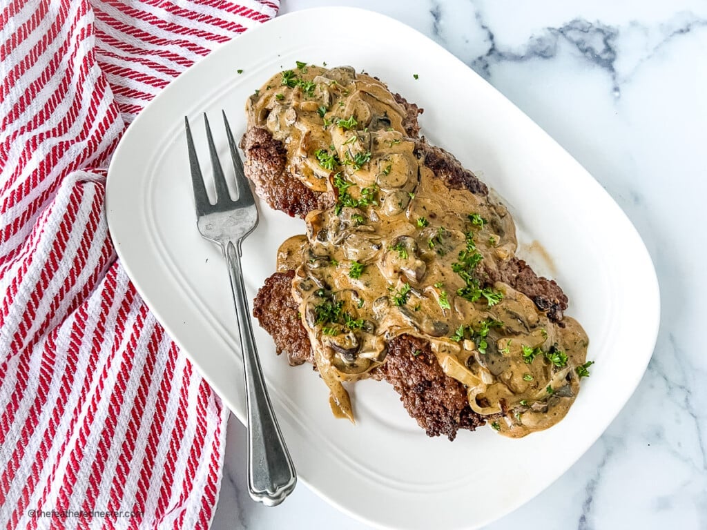Country style steak with mushroom gravy on a platter.
