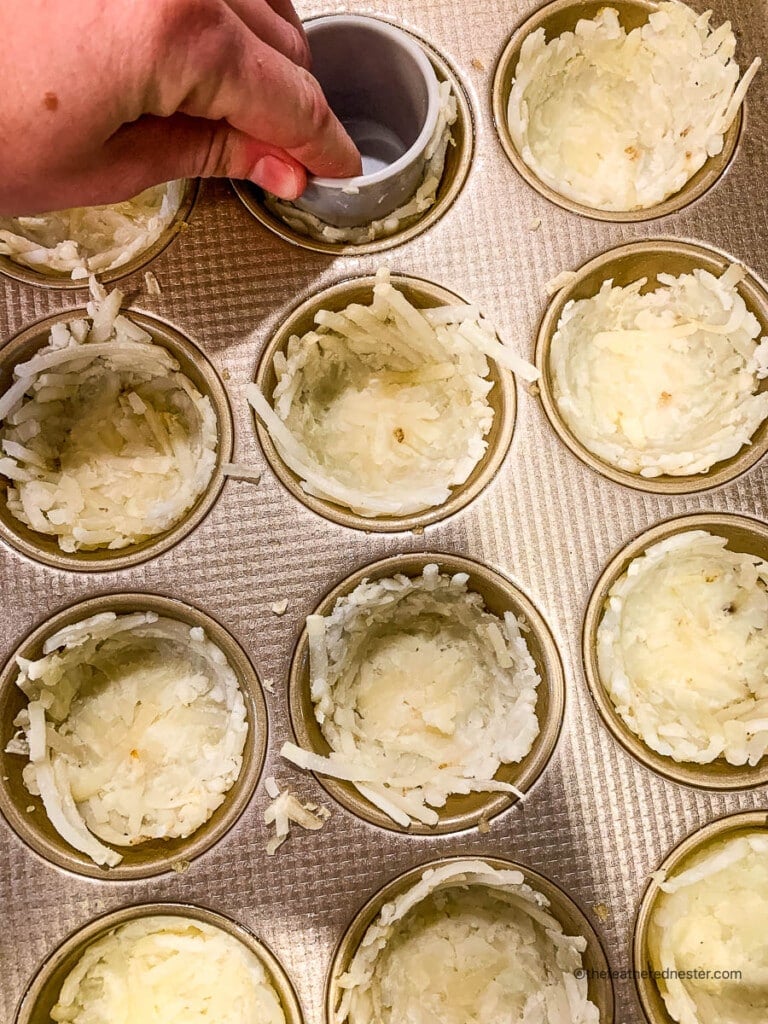 Using a shot glass to press hash browns into muffin tins so they look like birds nests.