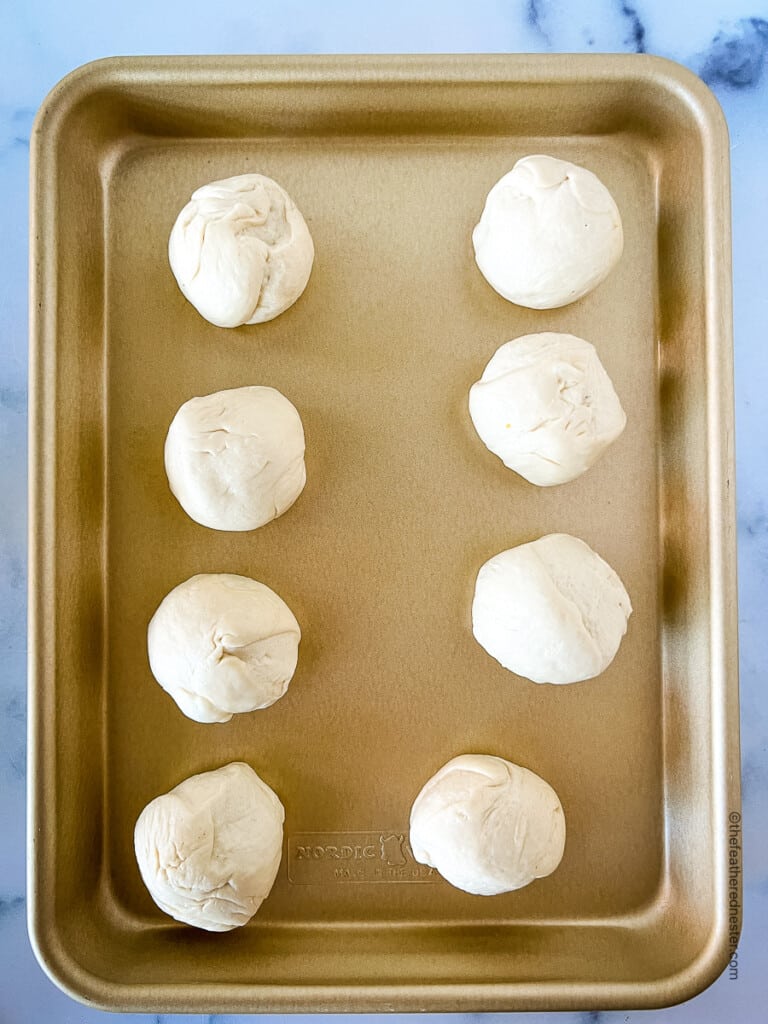 a baking sheet with 8 dough balls.