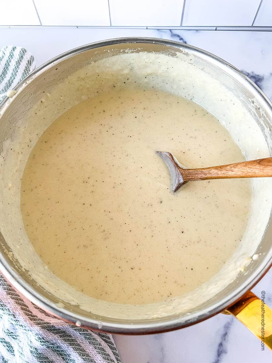 saucepan full of white cheddar cheese sauce.