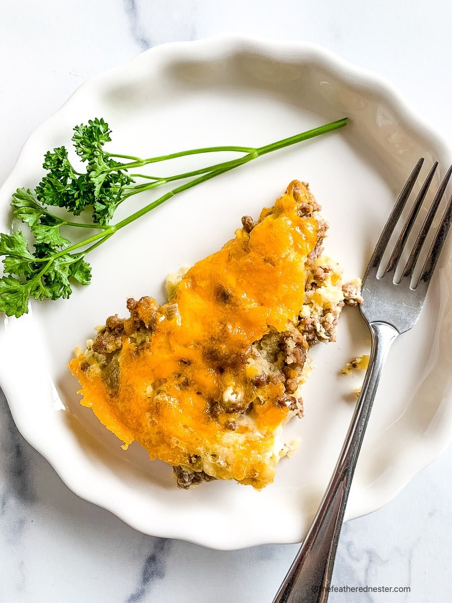 Plated slice of savory cheeseburger pie garnished with fresh parsley.