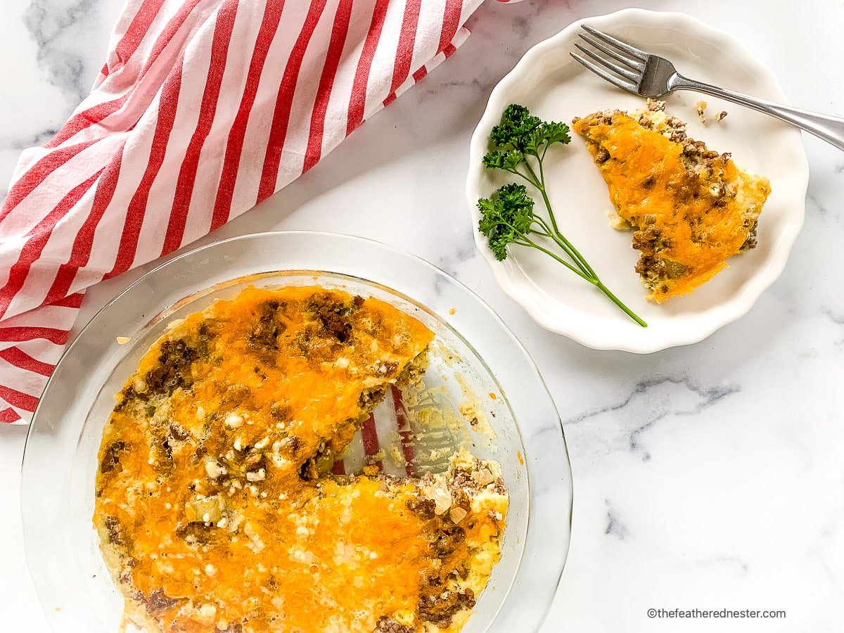 A pan of bisquick cheeseburger pie with a plate with 1 slice and fork