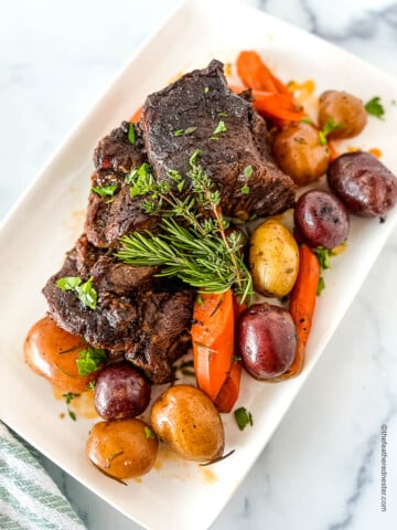 a white serving plate with Dutch Oven Pot Roast and vegetables.