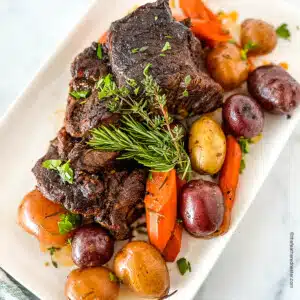square photo of a white serving plate with Dutch Oven Pot Roast and vegetables.
