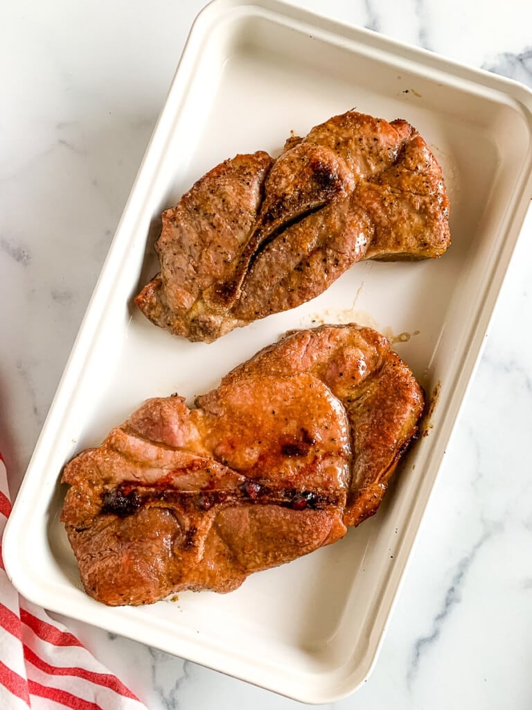 Pork steak in oven safe baking dish.