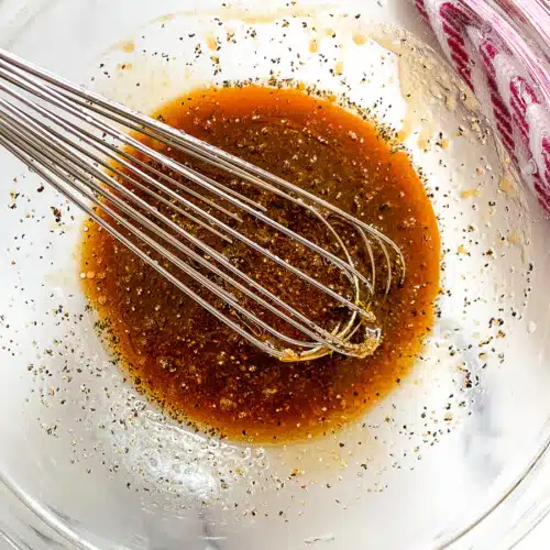 Whisking pork marinade ingredients in a glass mixing bowl.