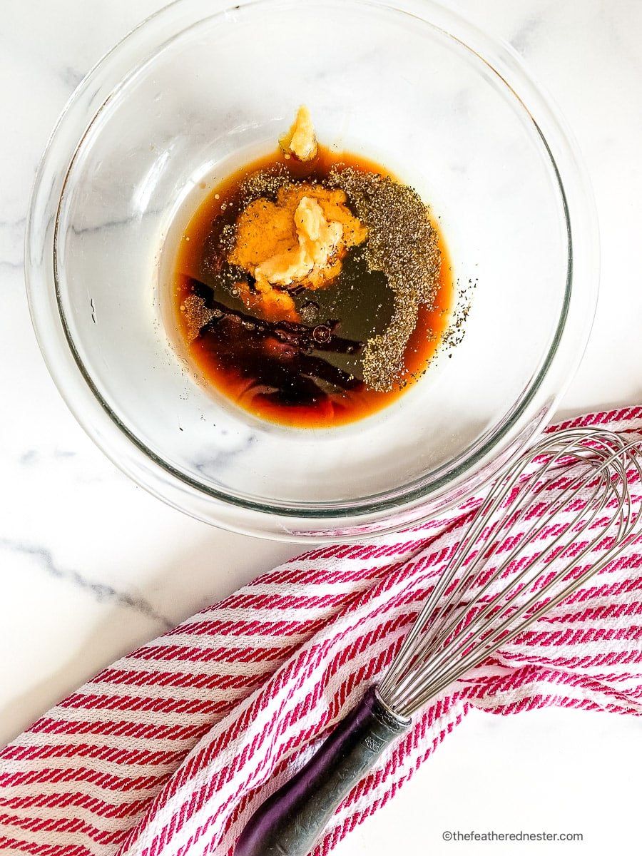 Fresh ginger and soy sauce in a glass mixing bowl with spices.