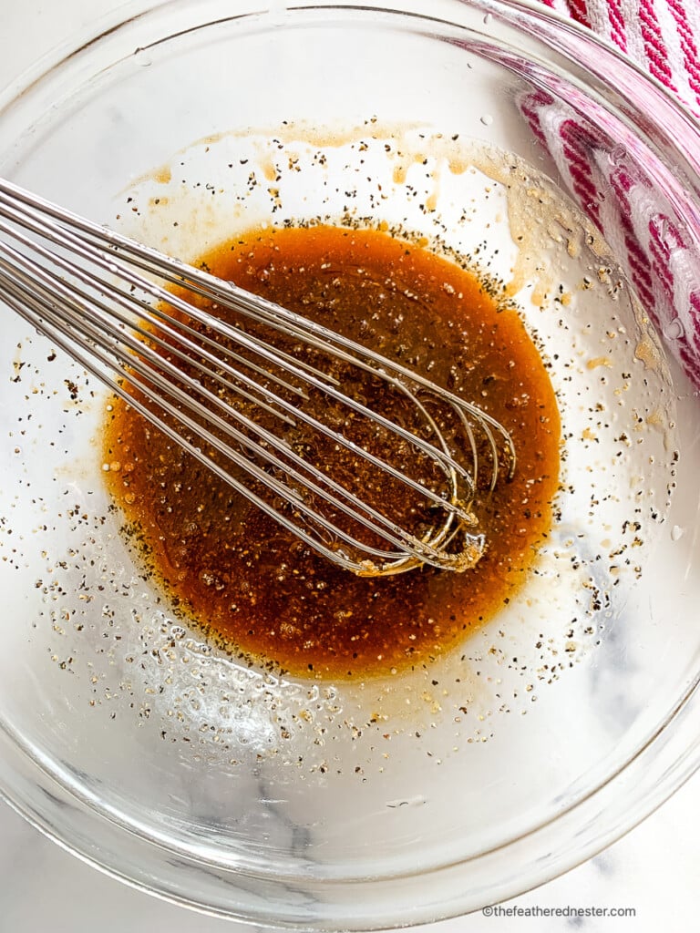 Whisking ingredients in a glass mixing bowl for an easy pork chop marinade.