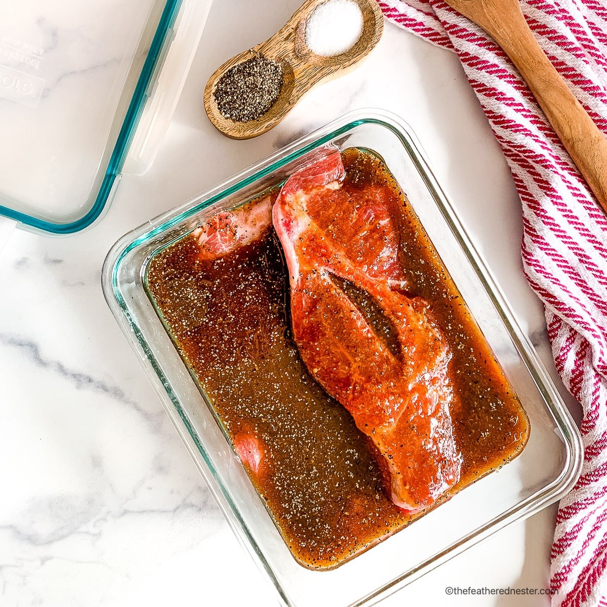 Pork steaks marinading in a dish.