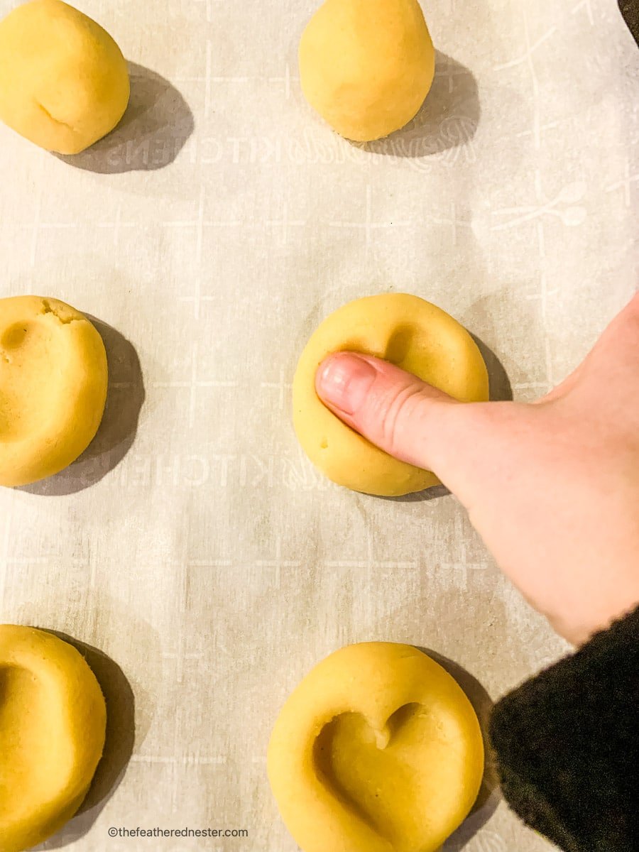 using thumb to create imprints in dough.