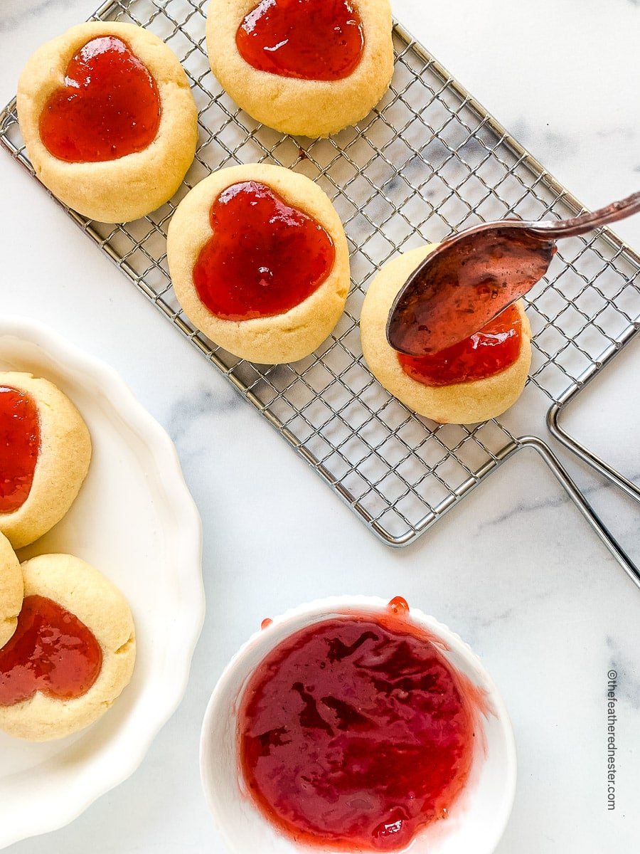 filling heart jam cookies with red preserves.