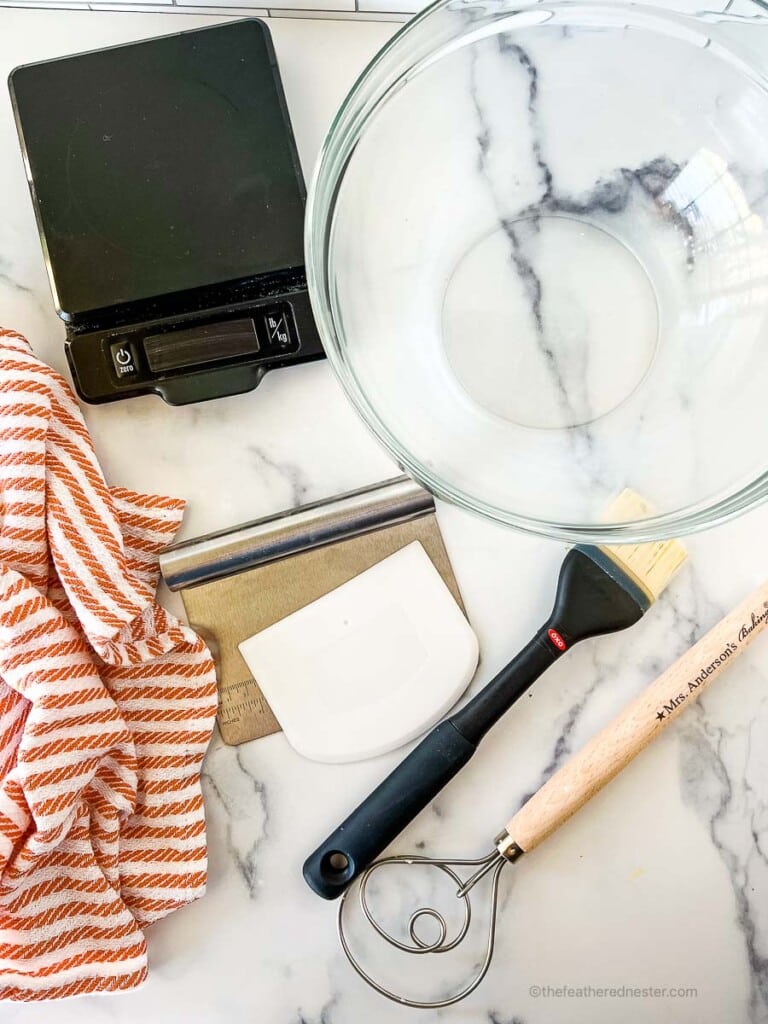 digital kitchen scale, mixing bowl and other tools for baking bread.