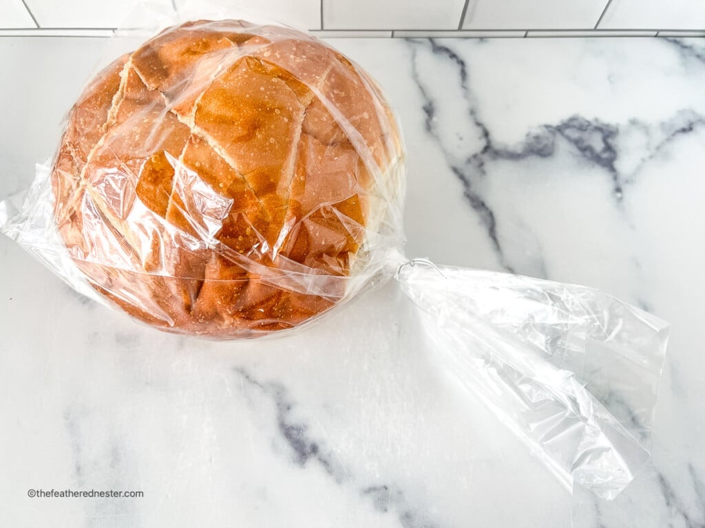 Round loaf of sourdough bread stored in a plastic bag.