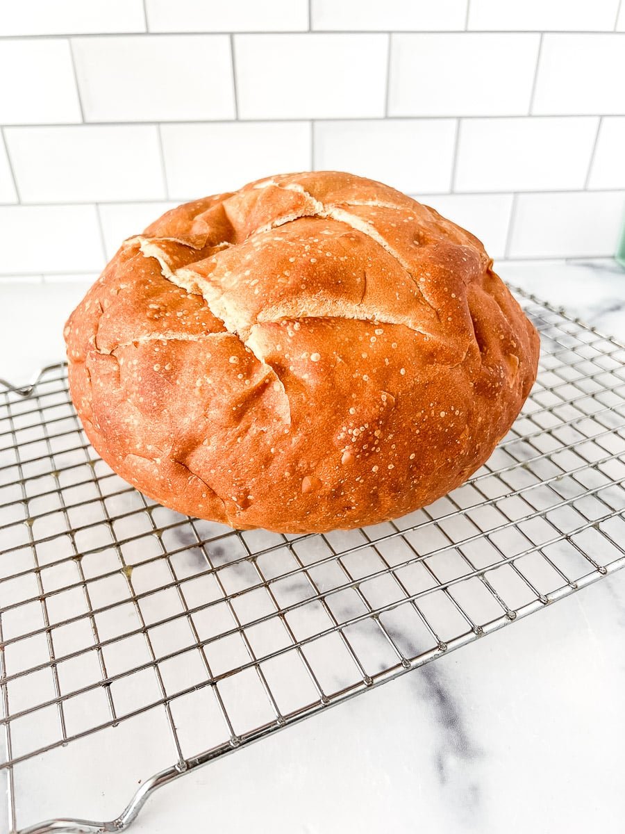 Loaf of artisan bread on a wire cooling rack.