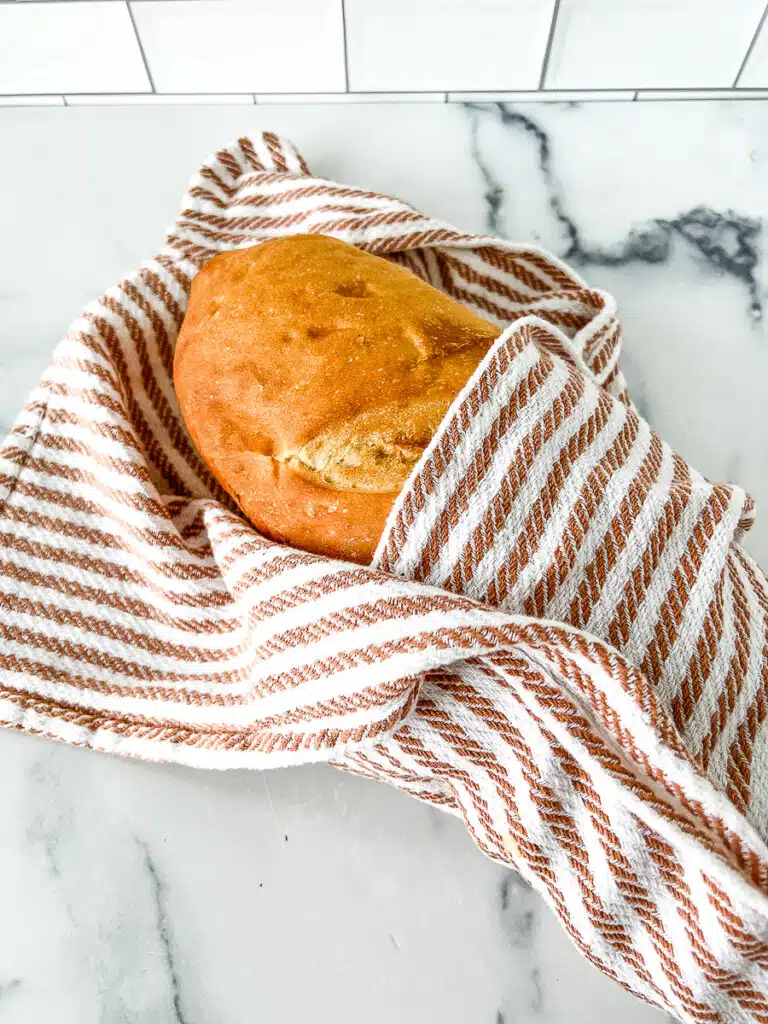 storing sourdough bread in a brown and white striped kitchen towel