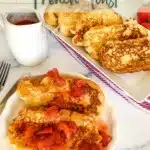A platter of French toast and a Plate of french toast topped with strawberries with a small pitcher of strawberry sauce