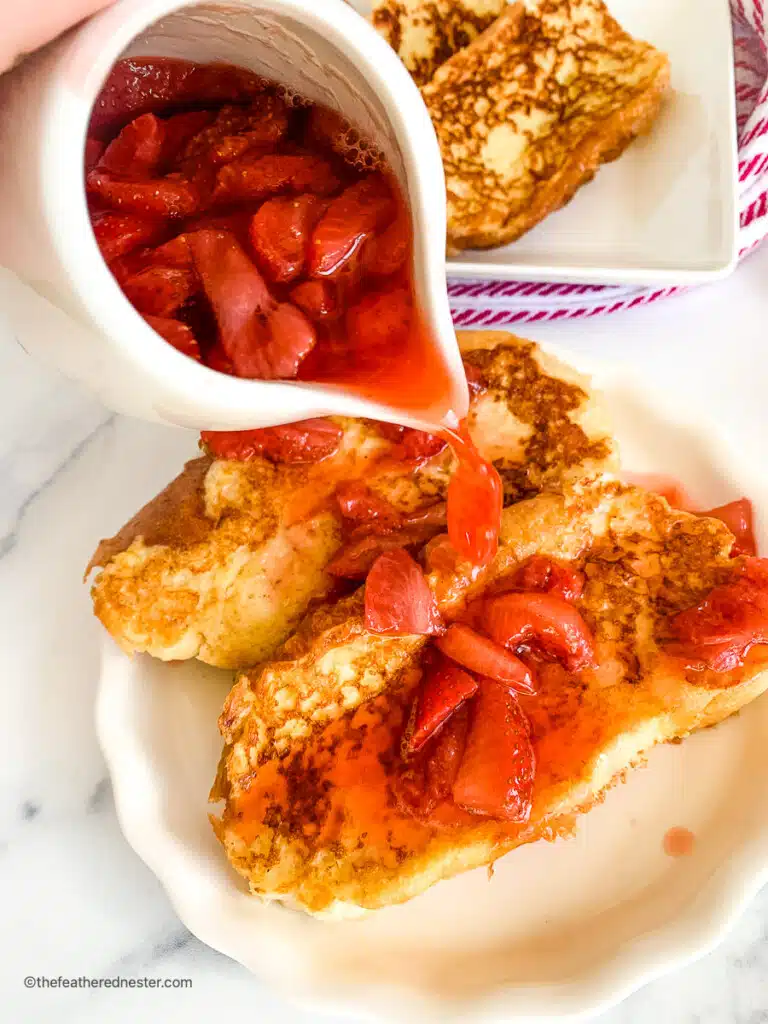 pouring fresh strawberry syrup onto strawberry French toast.
