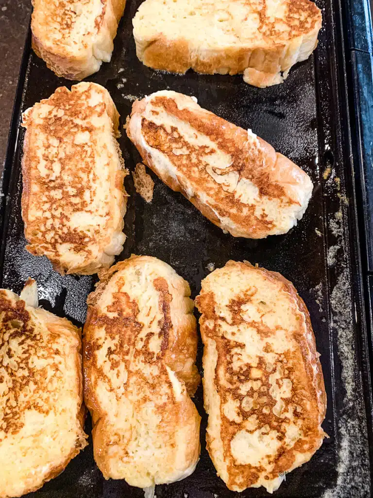 Cooking slices of french toast on a griddle.