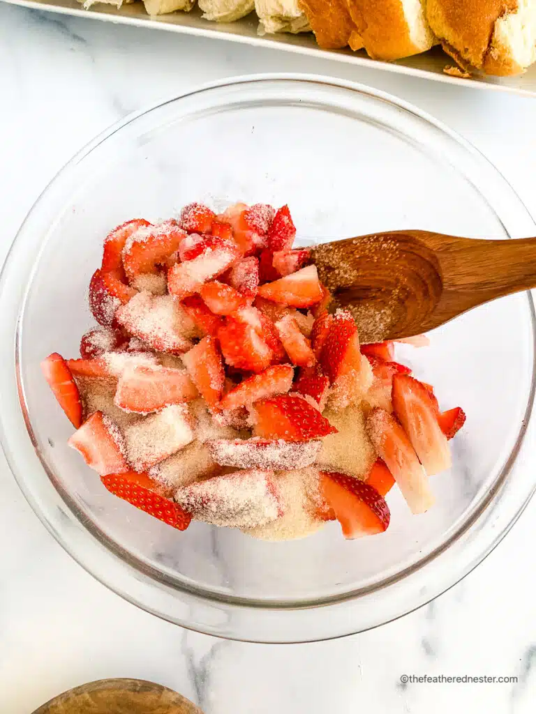 wooden spoon in a bowl of macerated strawberries.
