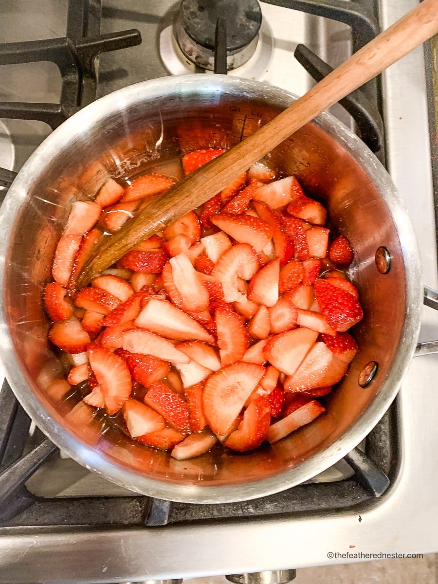 Strawberry syrup for French toast cooking in a saucepan.