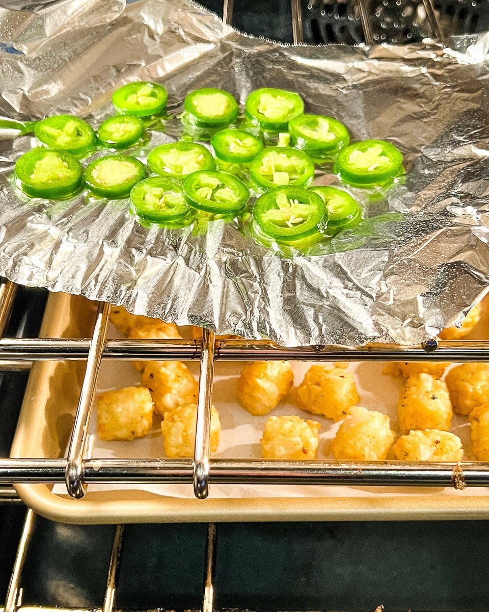 roasting jalapeno slices in oven above tachos.