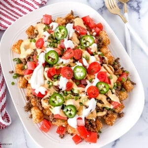 Loaded tater tots on a white platter.