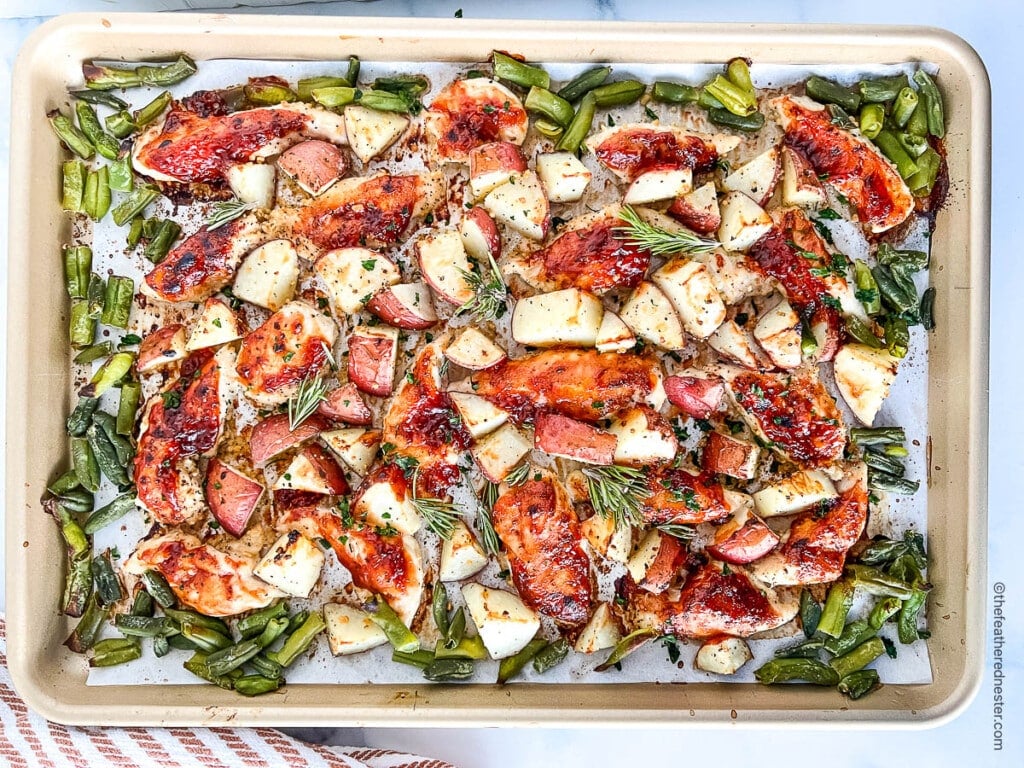 Pan of perfectly roasted vegetables and meat coated in BBQ sauce.