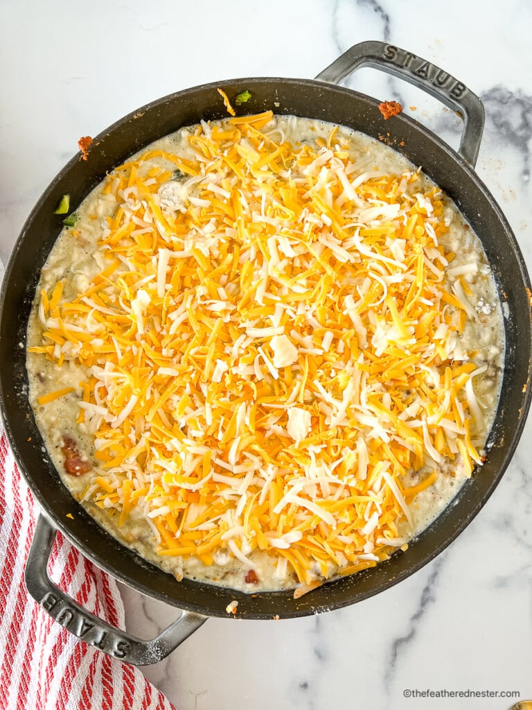 Shredded cheese on top of an uncooked breakfast bake.
