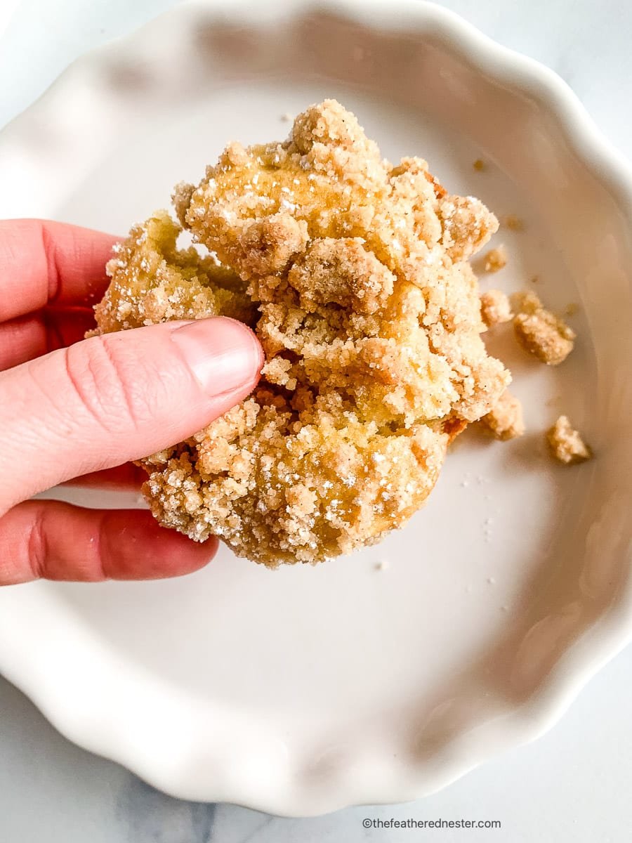 Woman's hand holding cinnamon streusel muffins.