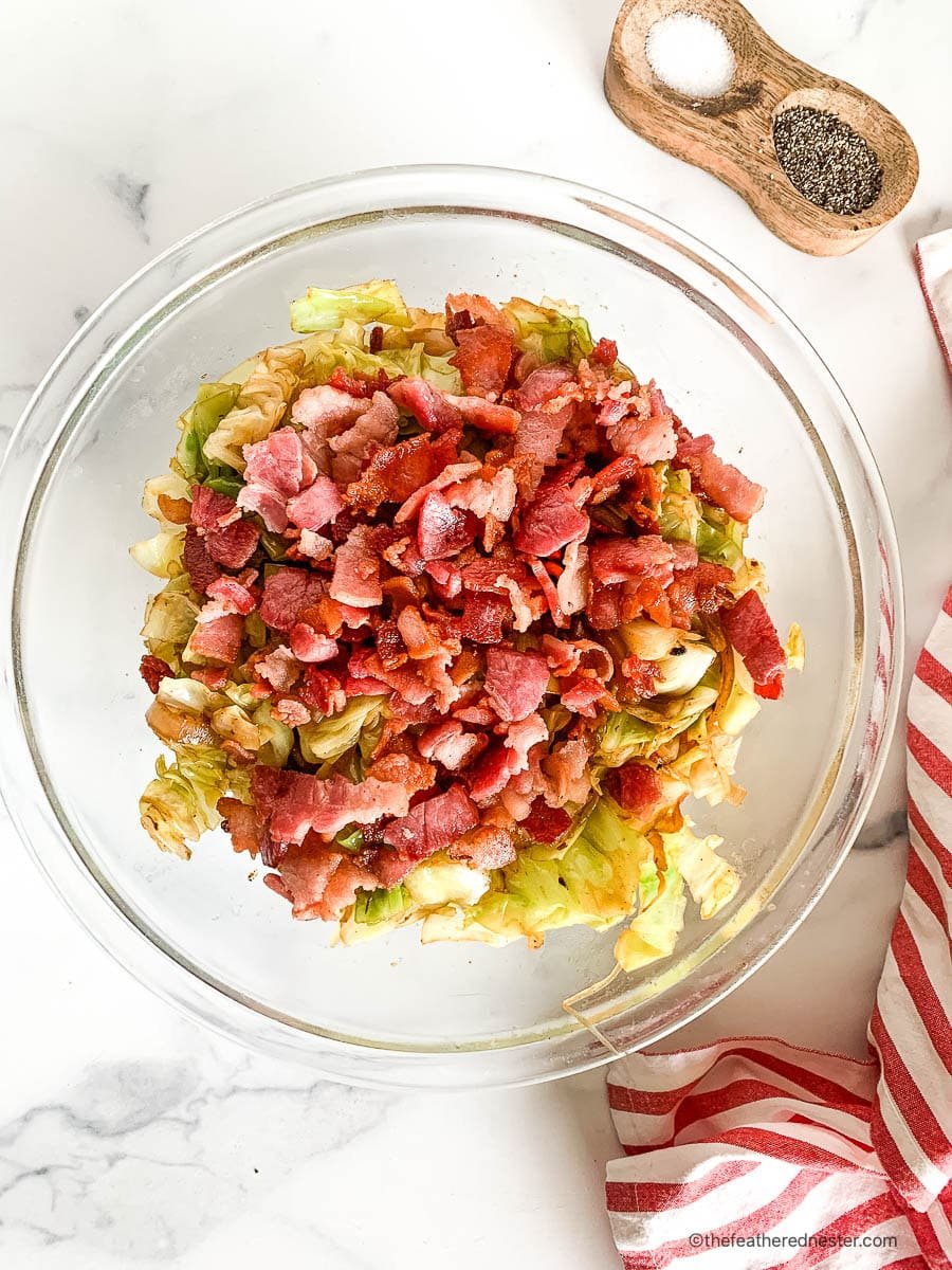 Fried cabbage with bacon in a large glass serving bowl.