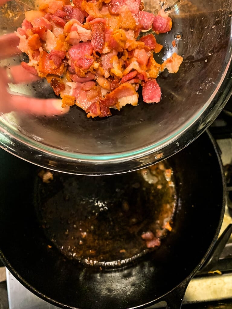 Crispy bacon pieces in glass bowl above pan of bacon grease.
