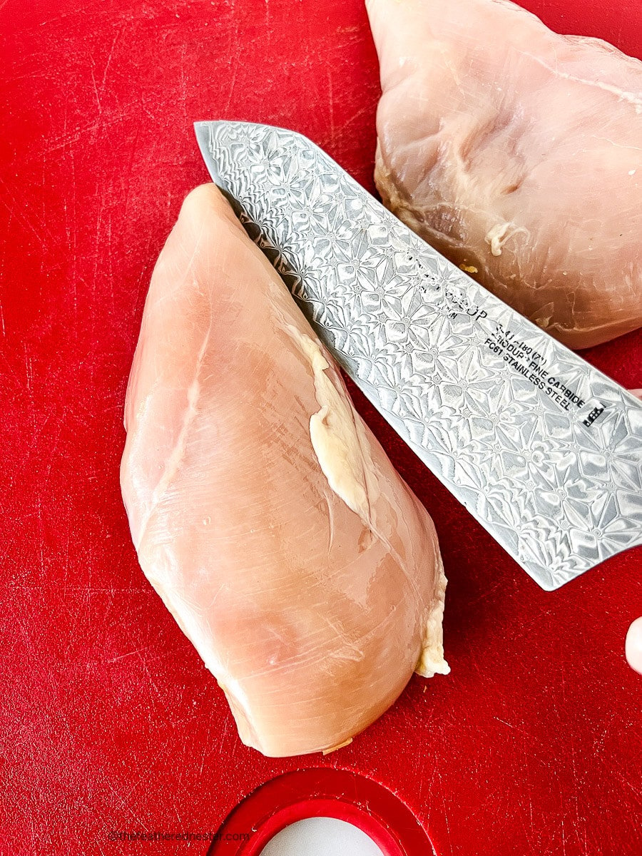 Using a knife to butterfly chicken breast.