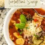 A bowl of tortellini soup with a bowl of shredded cheese on the side, with text on the upper part that says, "Instant pot tortellini soup www.thefeatherednester.com"