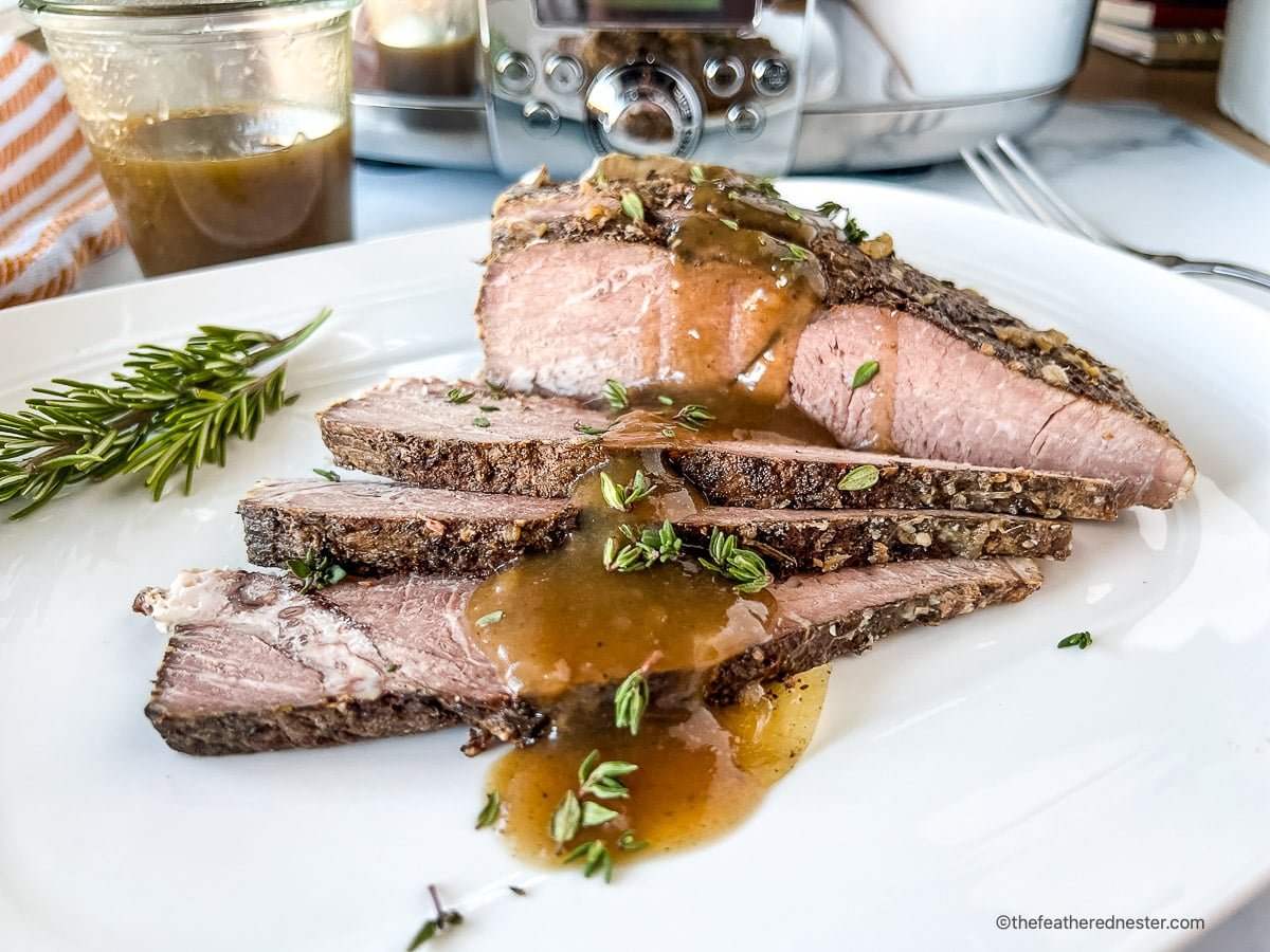 A plate of sirloin tip roast topped with sauce and parsley