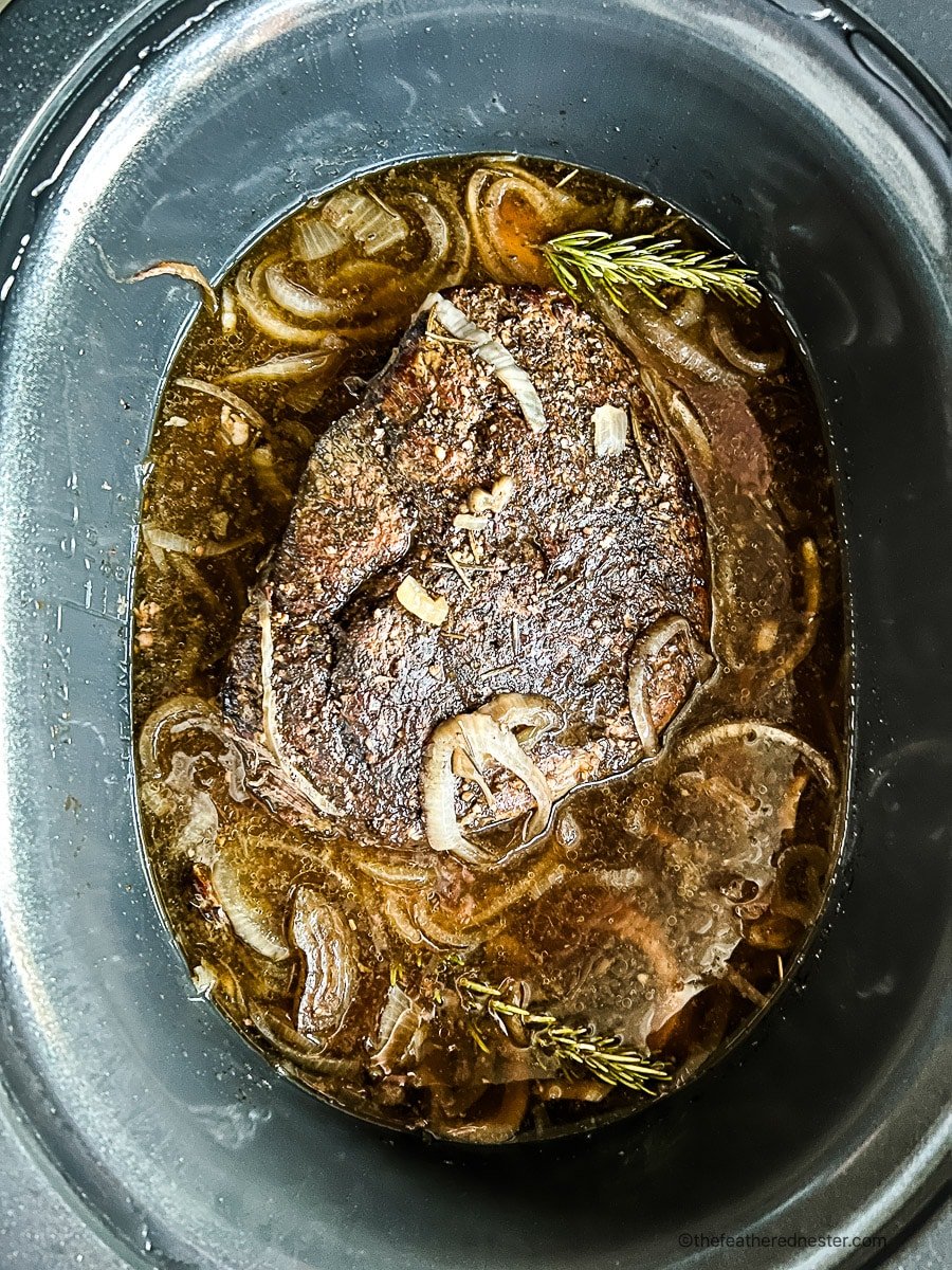 Slow cooked sirloin tip roast in crock pot with beef stock and onions.