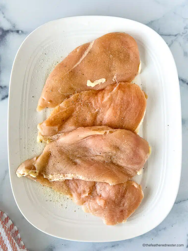 Uncooked seasoned poultry on a white platter.