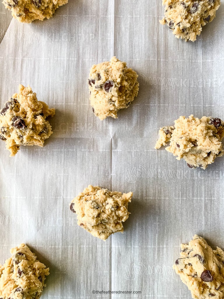 Raw scoops of cookie dough on a cookie sheet.