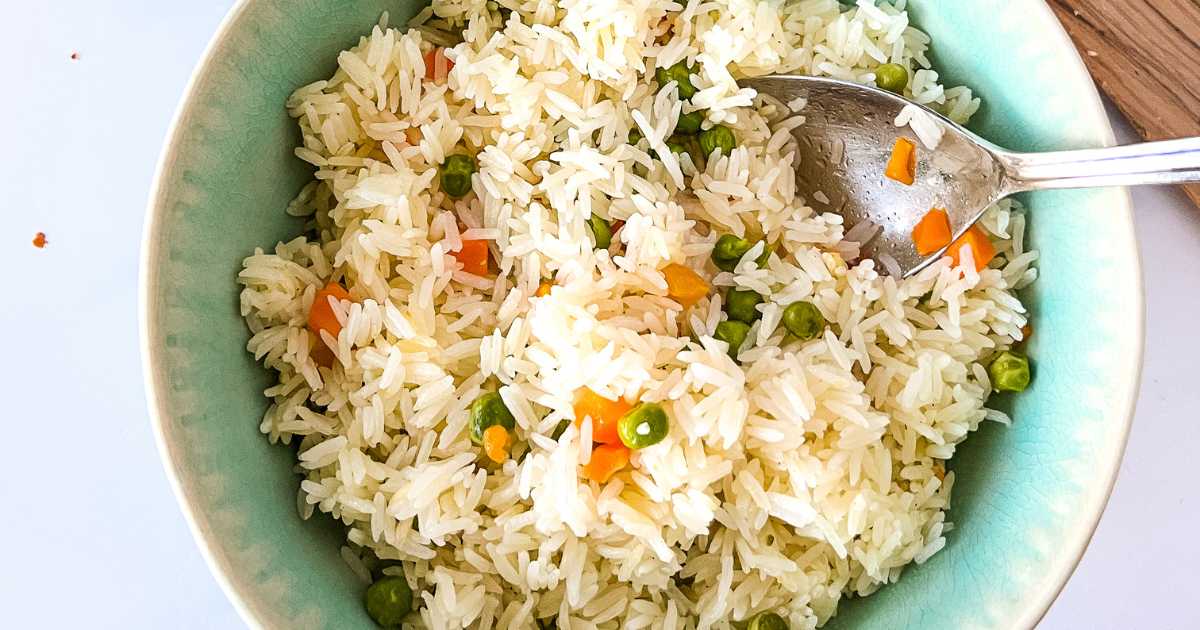 Spoon in a bowl of cooked vegetable rice.