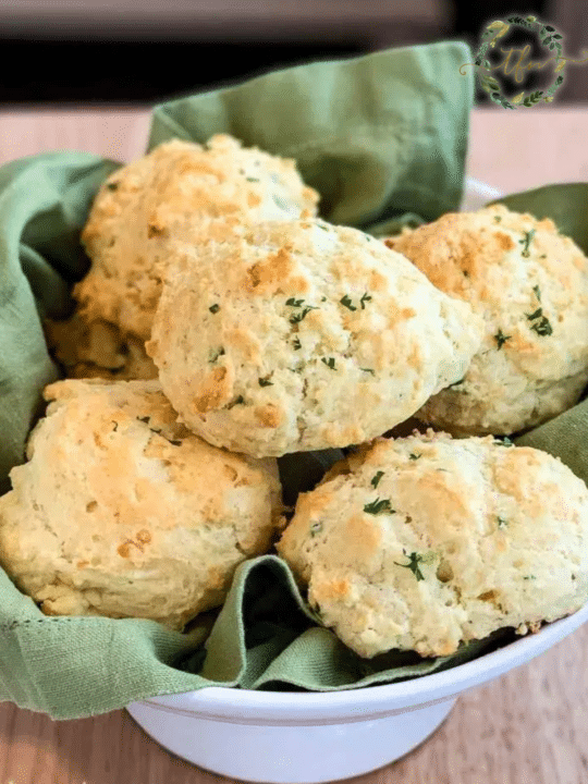 Jalapeno biscuits in a white serving bowl lined with a green kitchen towel.