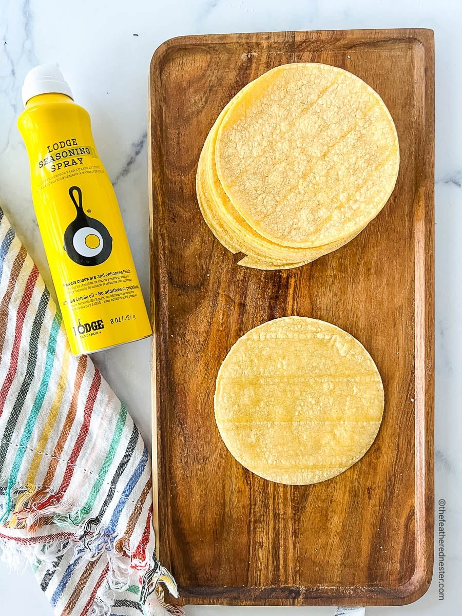corn tortillas on a wooden tray next to can of non-stick cooking spray.