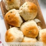 Batch of pull apart dinner rolls on a serving board and with a text on the bottom part that says, "old fashioned yeast rolls www.thefeatherednester.com"