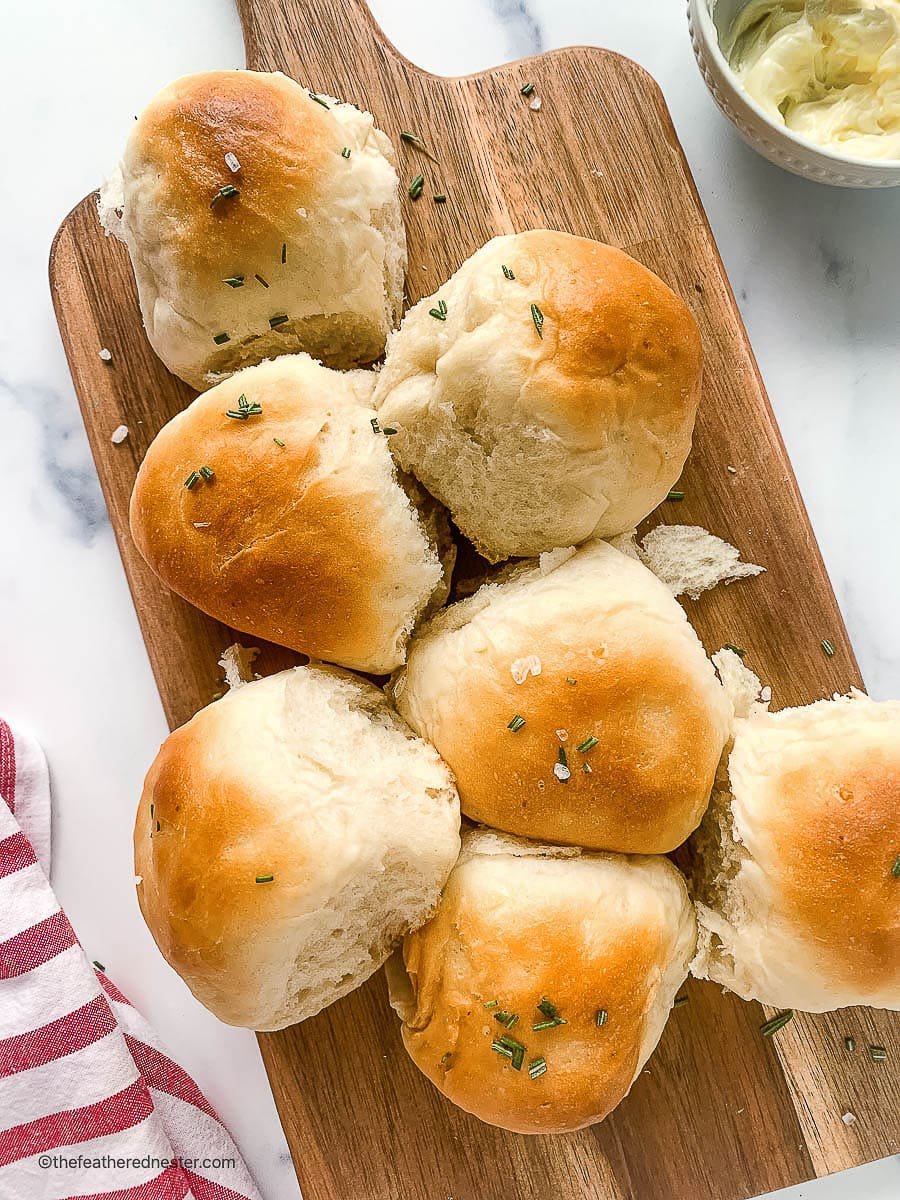 Old fashioned dinner rolls on a bread serving board.