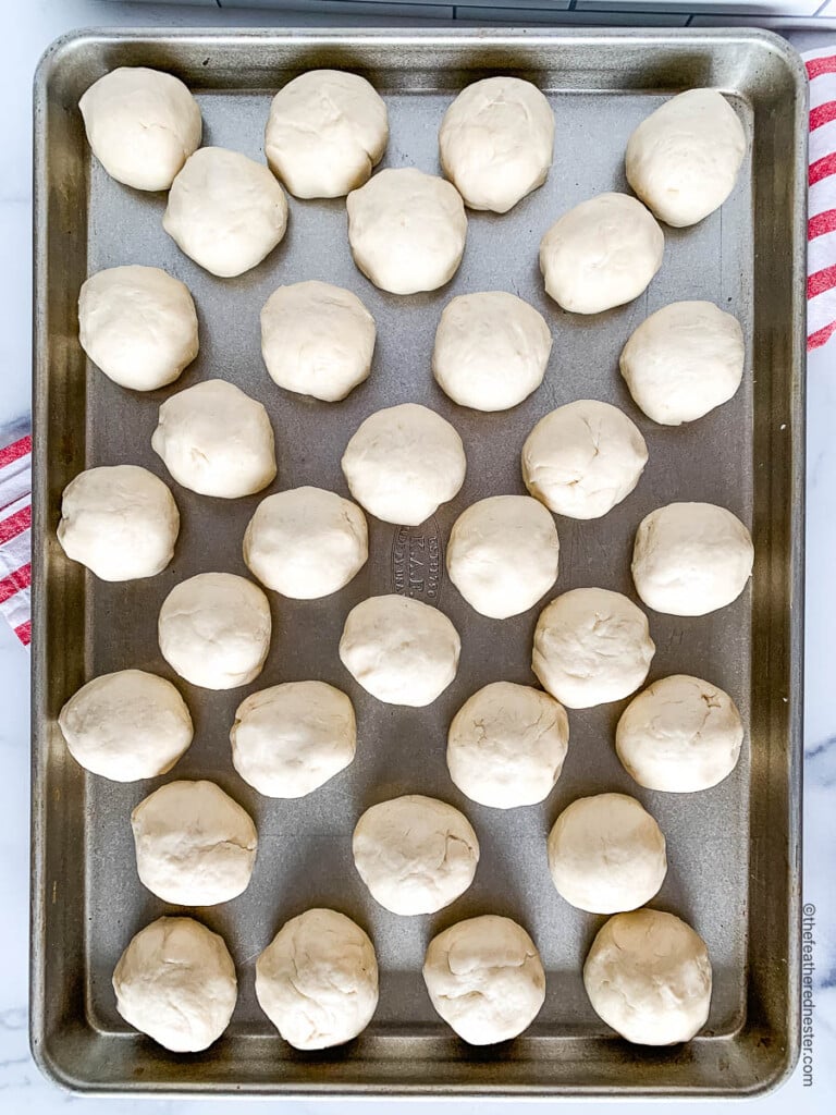 Balls of yeast dinner roll dough on a baking sheet.