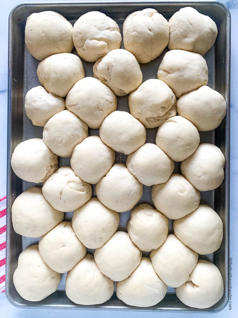 Unbaked balls of old fashioned yeast roll dough on a baking pan.