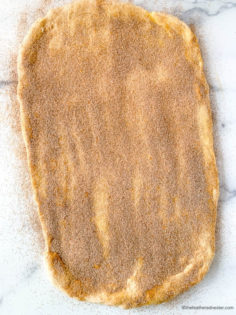 Cinnamon roll filling spread onto rectangle piece of dough.