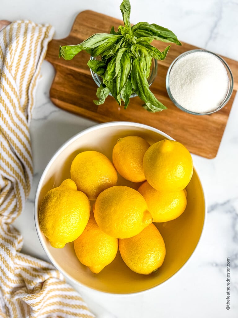 Bowls of fresh lemons, herbs and sugar for homemade lemonade recipe.