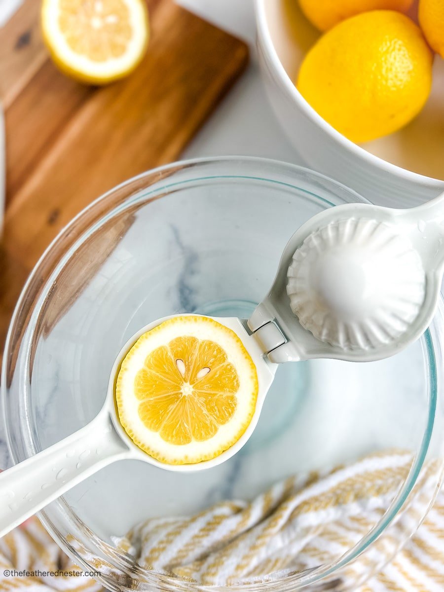 Squeezing fresh lemons in a glass bowl for homemade lemonade.