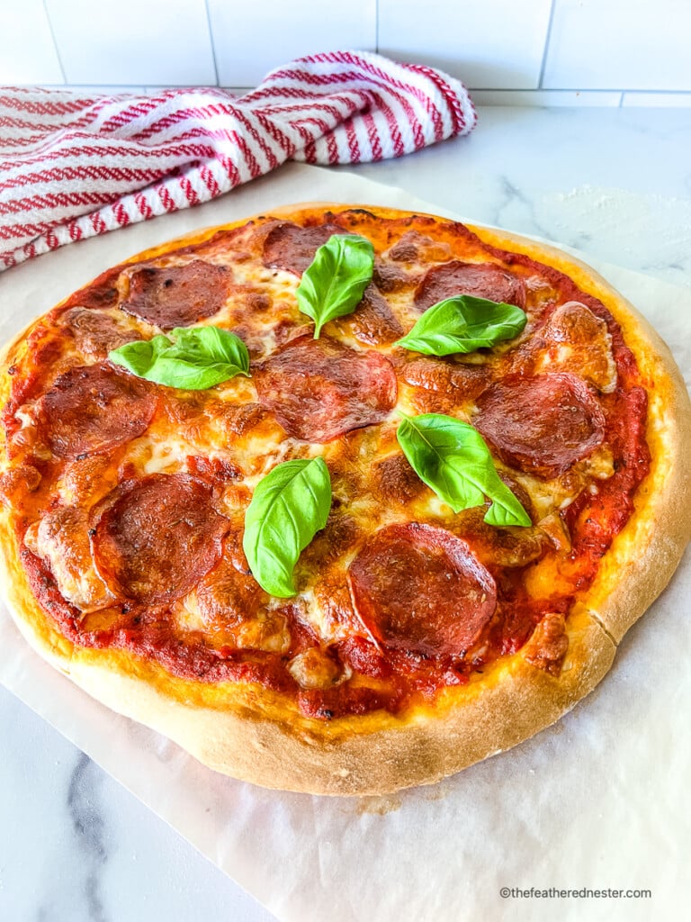 Homemade cheese and pepperoni pizza garnished with basil leaves.